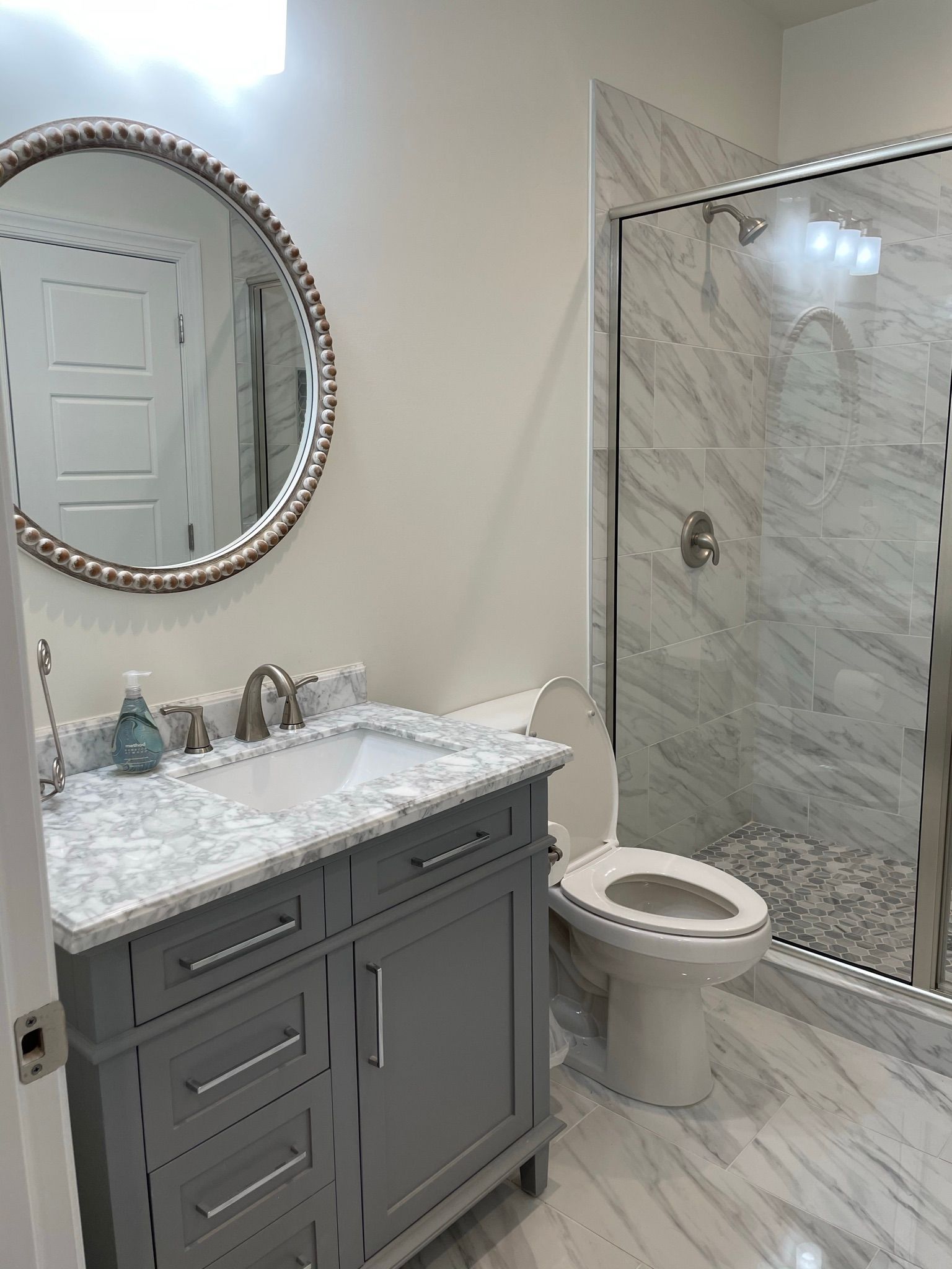 A bathroom with a sink , toilet , shower and mirror.