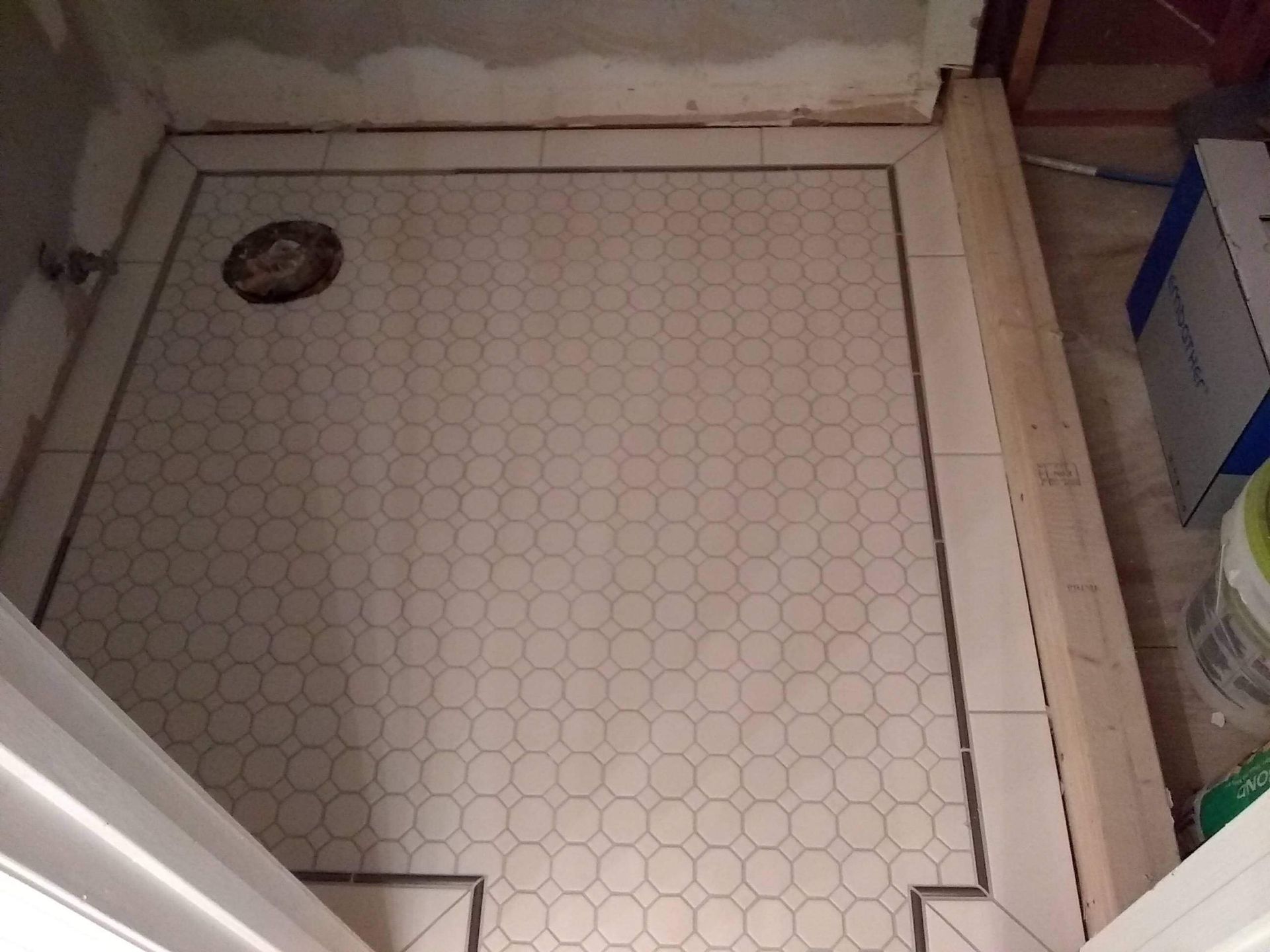 A bathroom with a hexagonal tile floor and a toilet