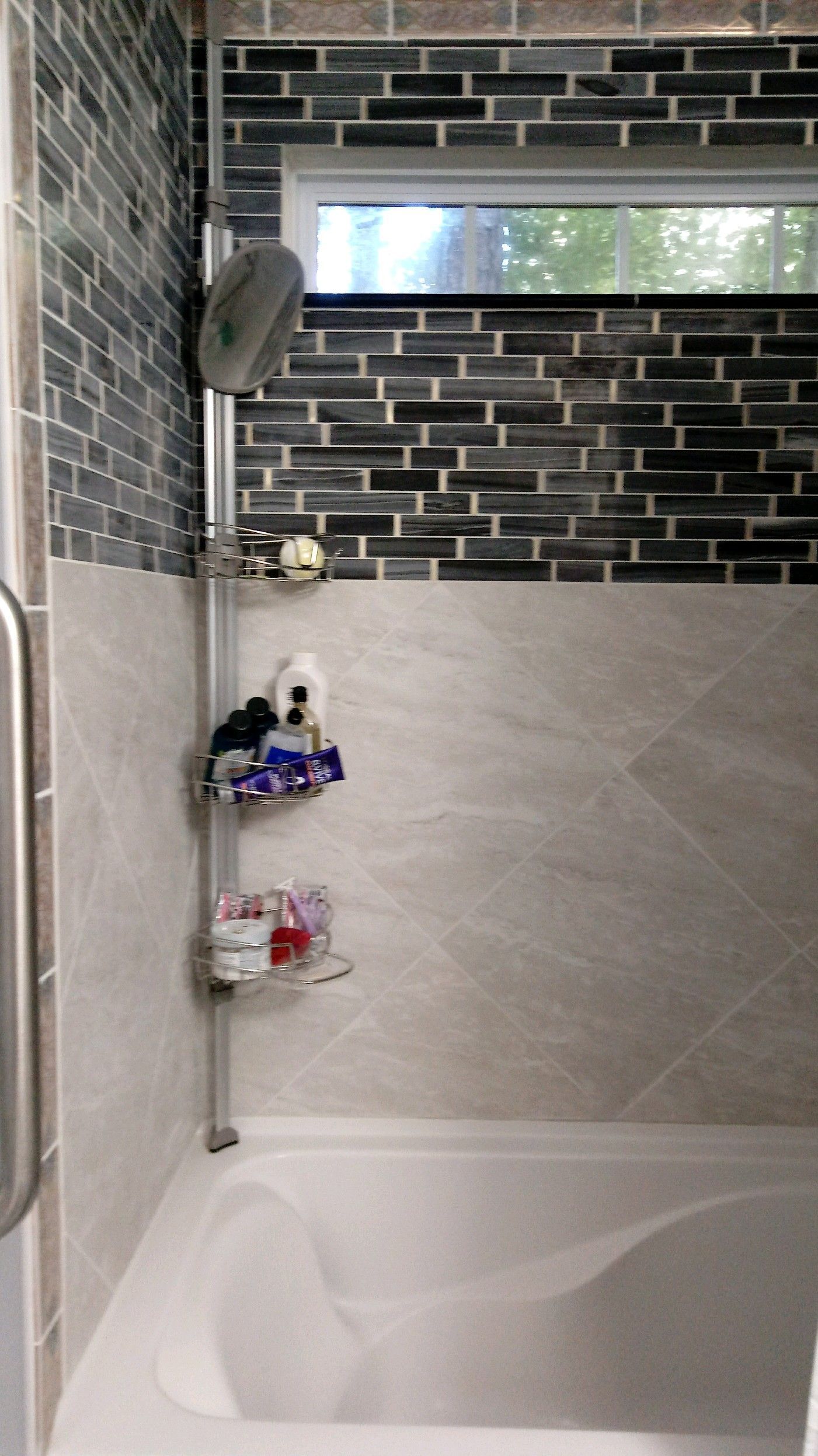 A bathroom with a tub and a shower with a brick wall