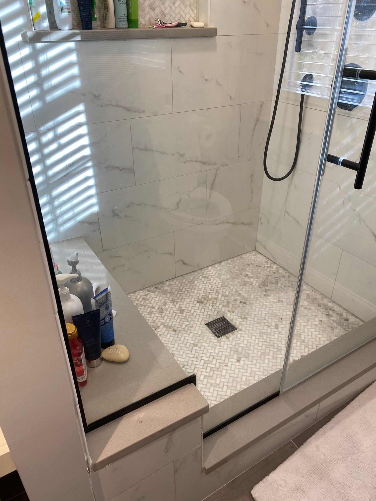 A bathroom with a walk in shower with a glass door