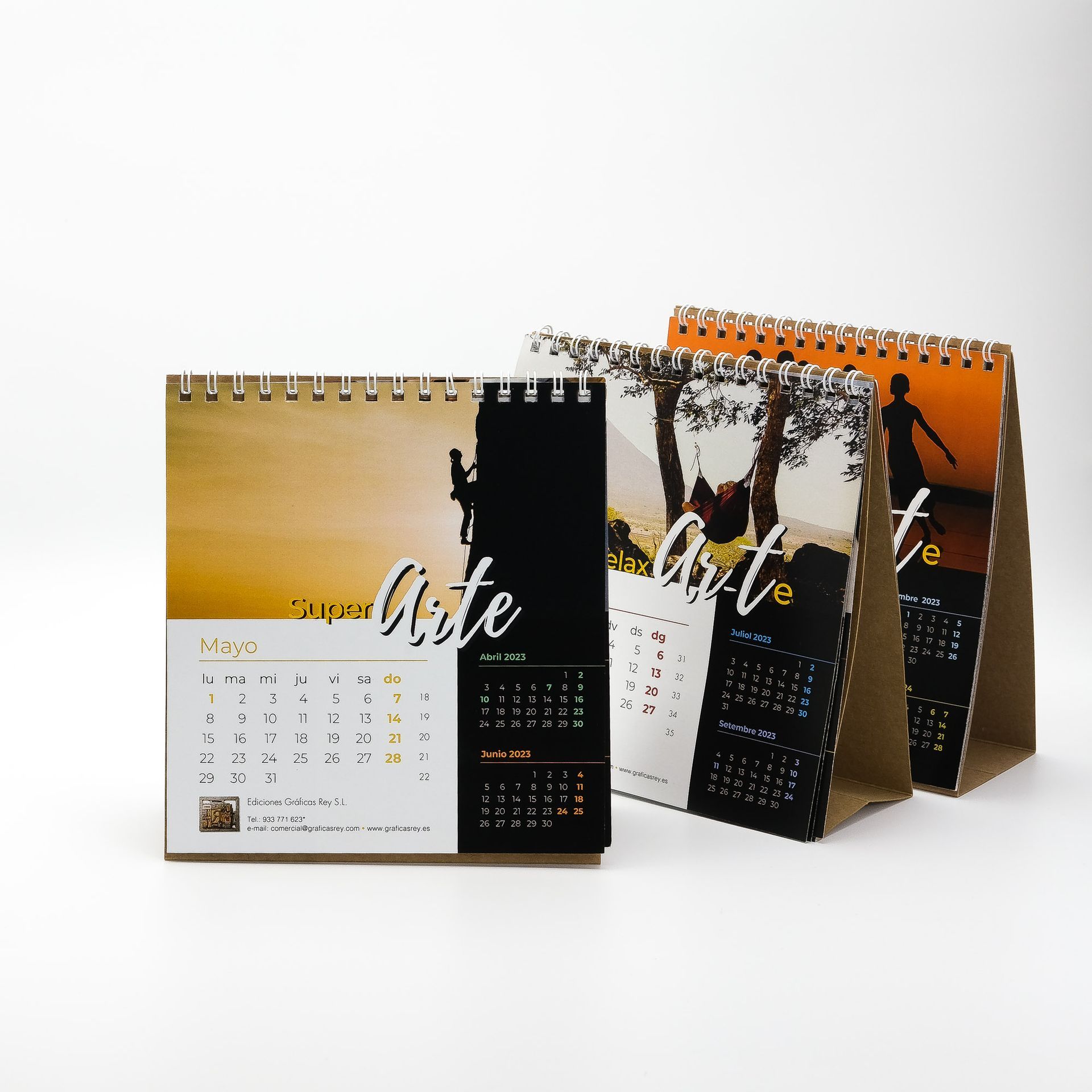 Tres calendarios están uno al lado del otro sobre una mesa.