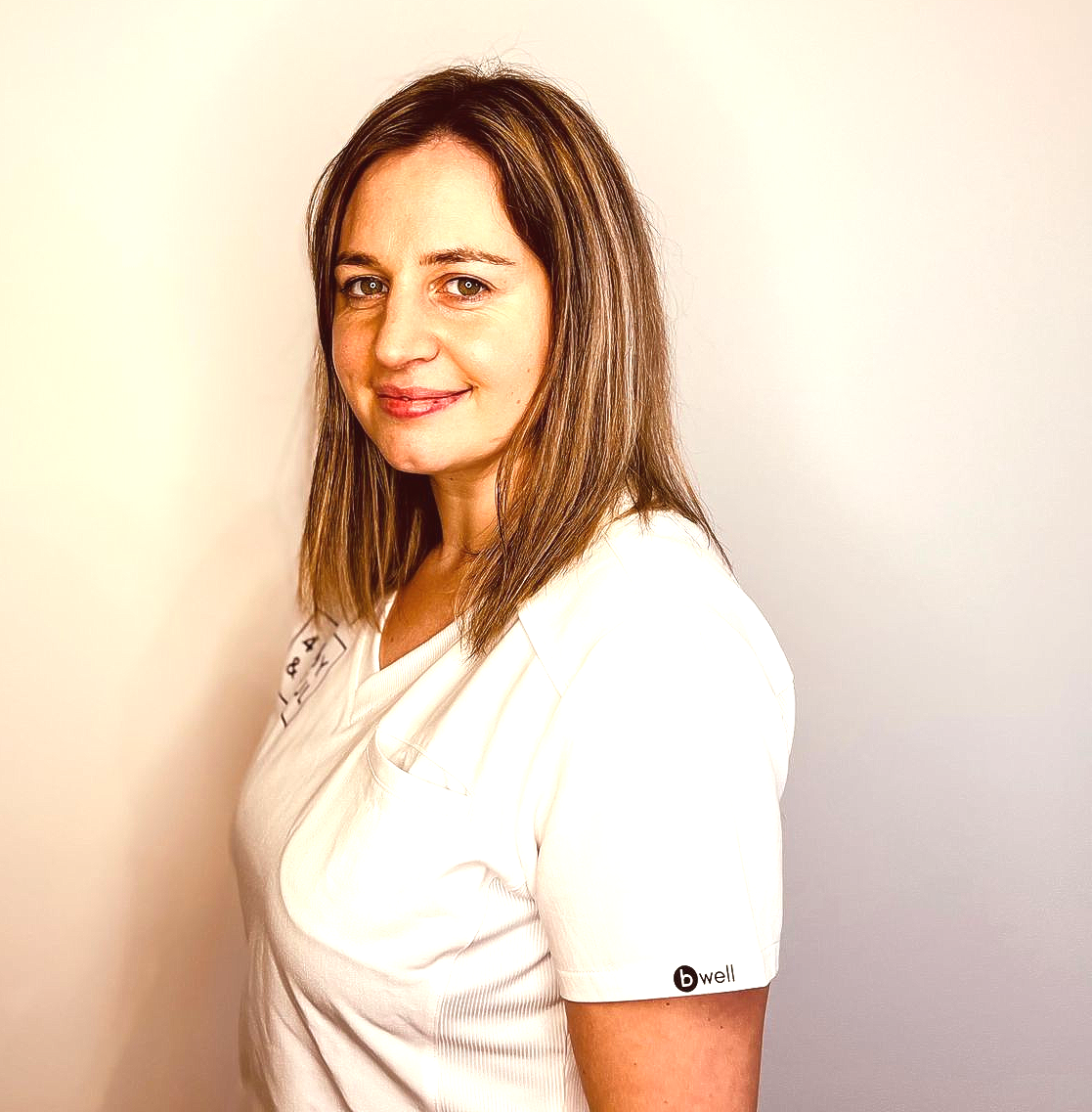 Eine Frau in einem weißen Hemd lächelt in die Kamera.