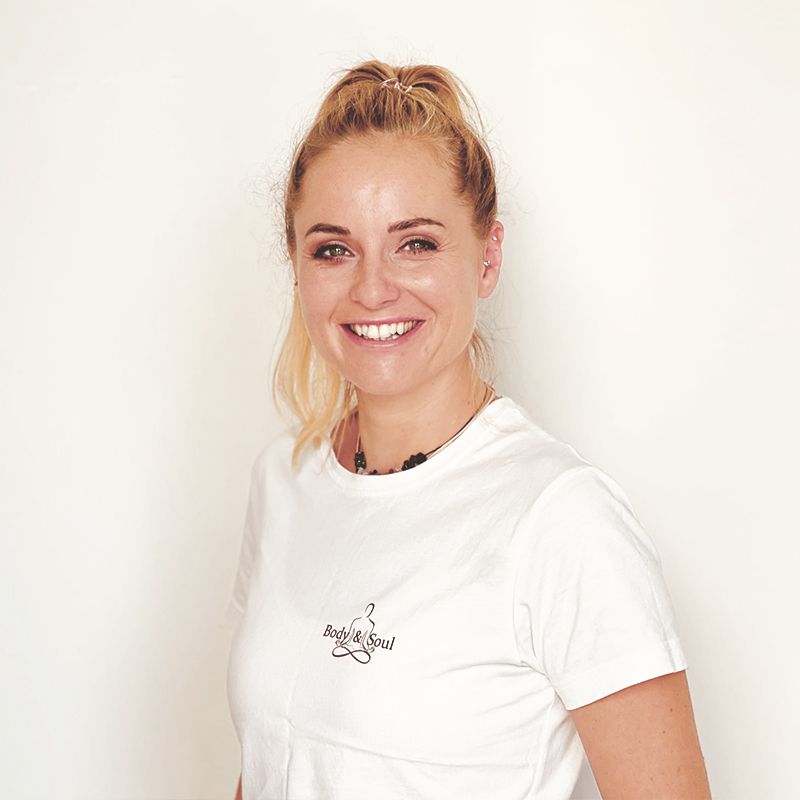 Eine Frau trägt ein weißes T-Shirt und lächelt in die Kamera.