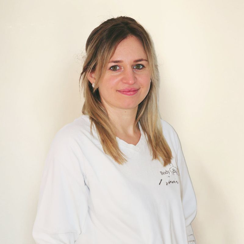 Eine Frau in einem weißen Hemd lächelt in die Kamera.