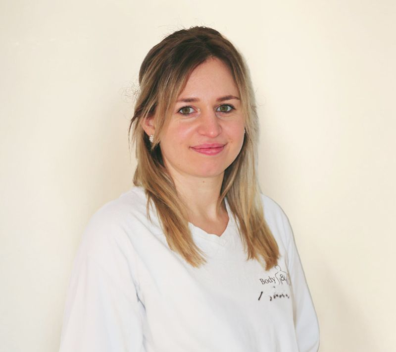 Eine Frau in einem weißen Hemd lächelt in die Kamera.