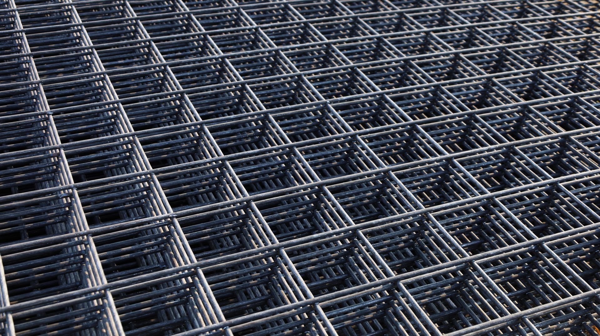 Close-up of a steel rebar grid, forming a square mesh pattern.