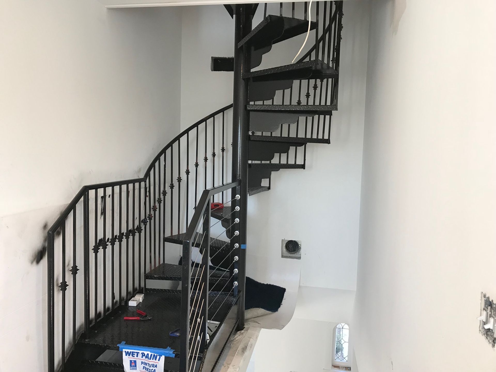 Black spiral staircase against white walls.