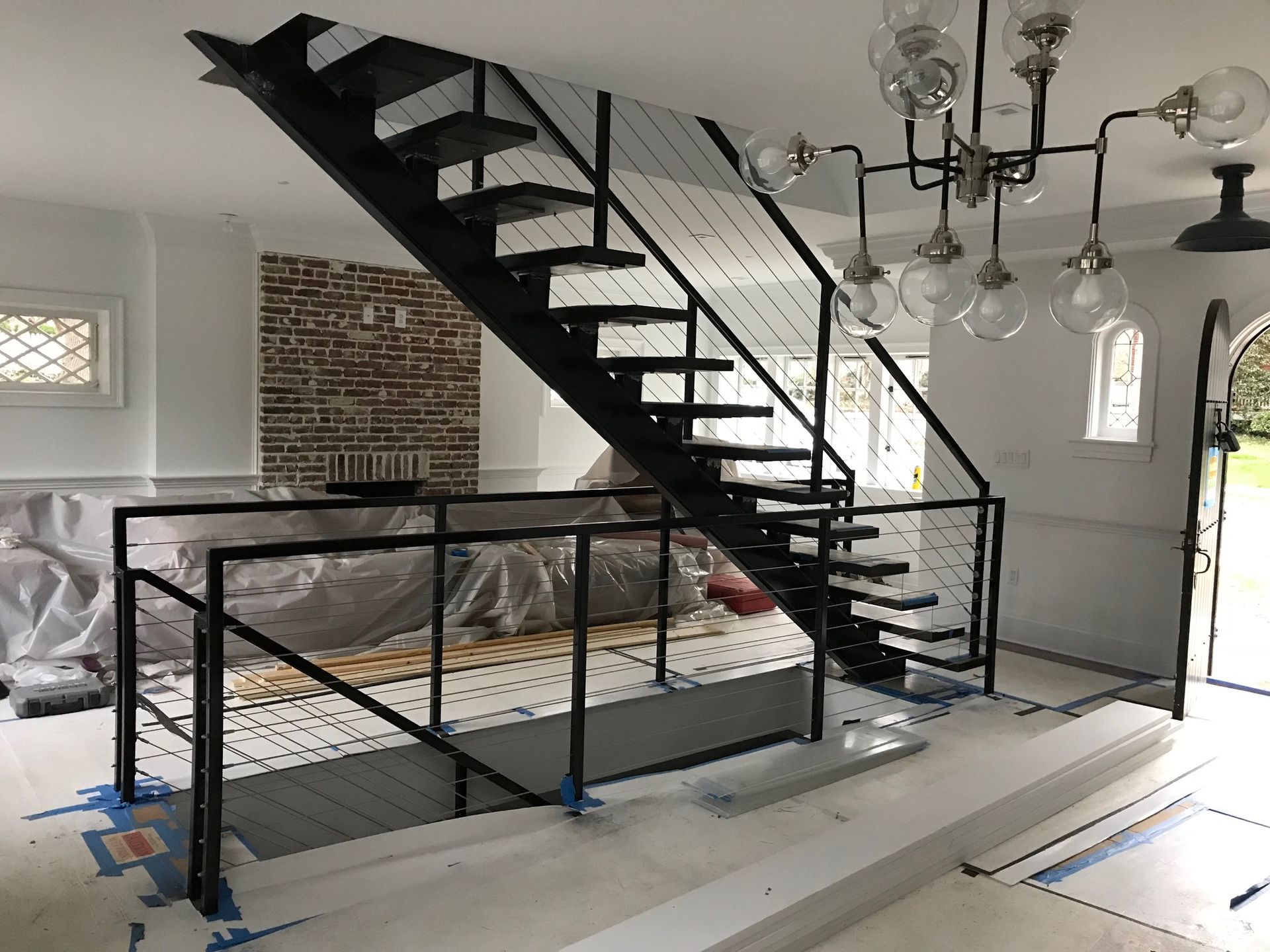 Black metal staircase with cable railing, indoors.
