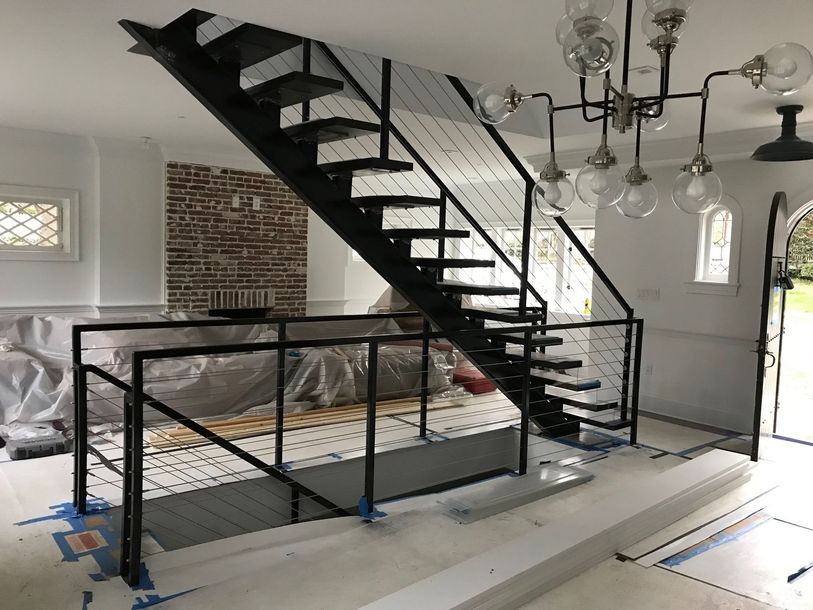 Black metal staircase with cable railing, indoors.