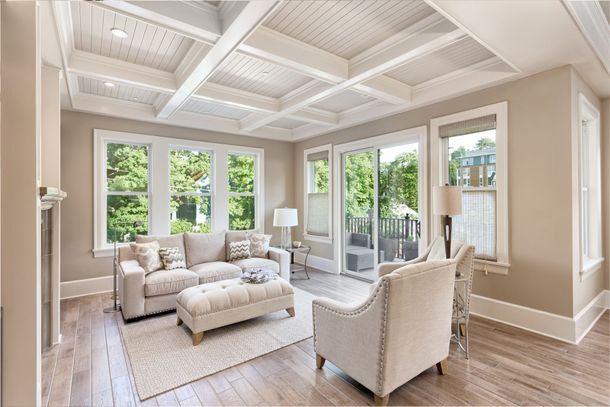 A living room with a couch , chairs , ottoman and sliding glass doors.
