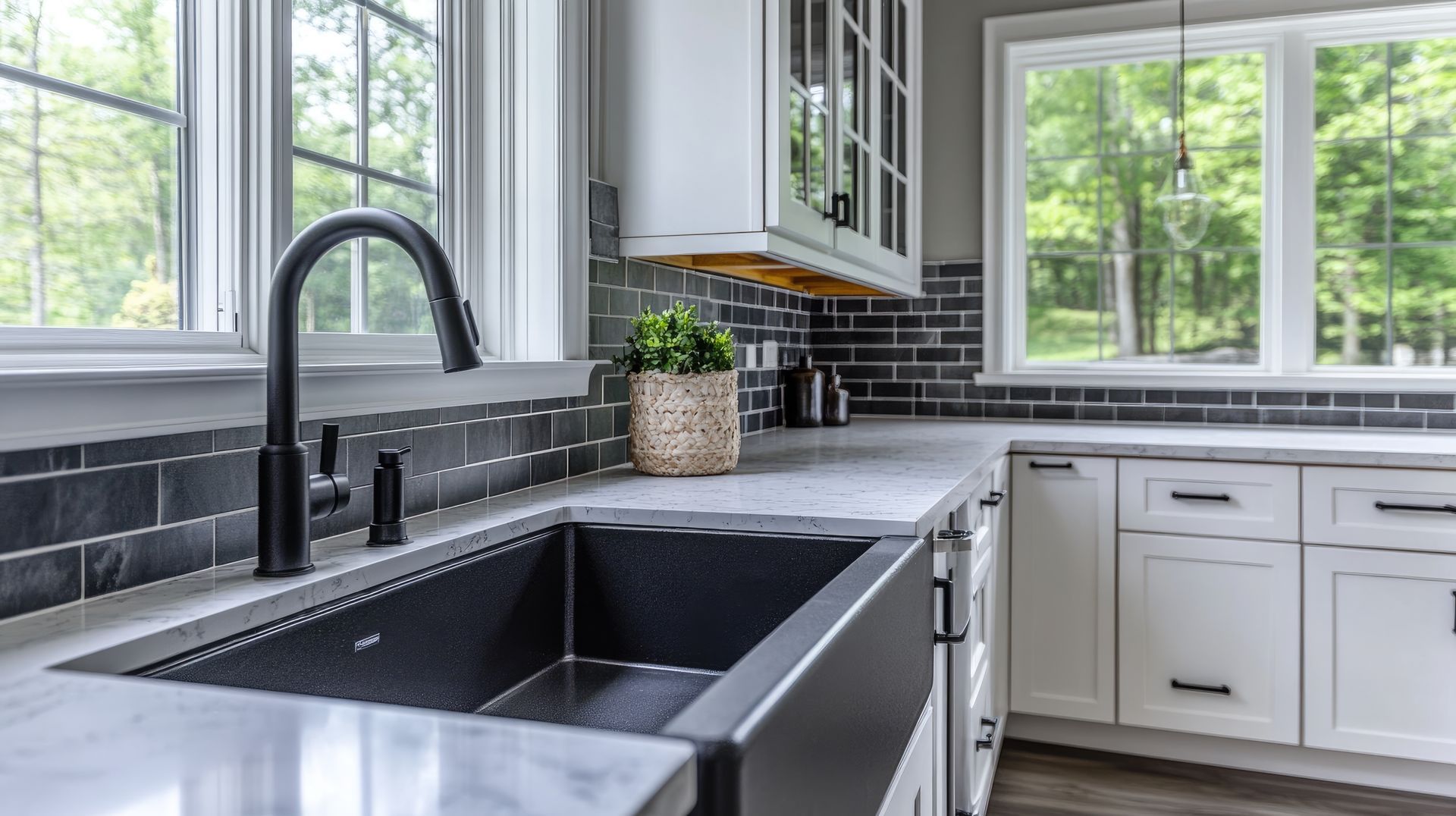 A kitchen with a black sink and white cabinets.