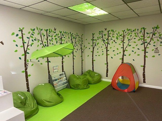 Reading nook with beanbag chairs, tree mural, tent, and green awning.