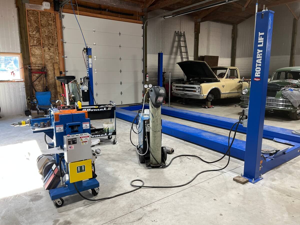 A garage with a lot of equipment and a truck with the hood up.