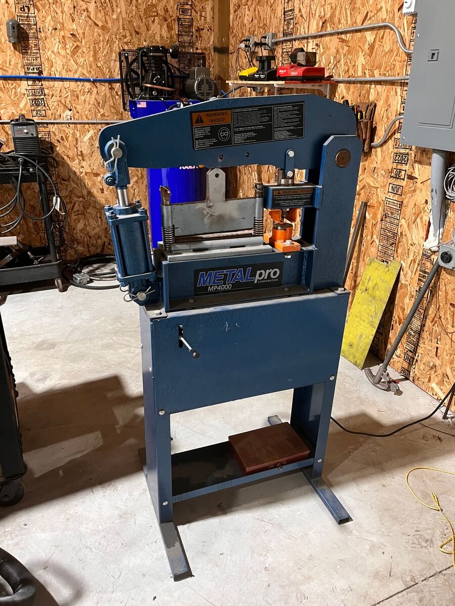 A blue machine is sitting in a garage next to a wooden wall.