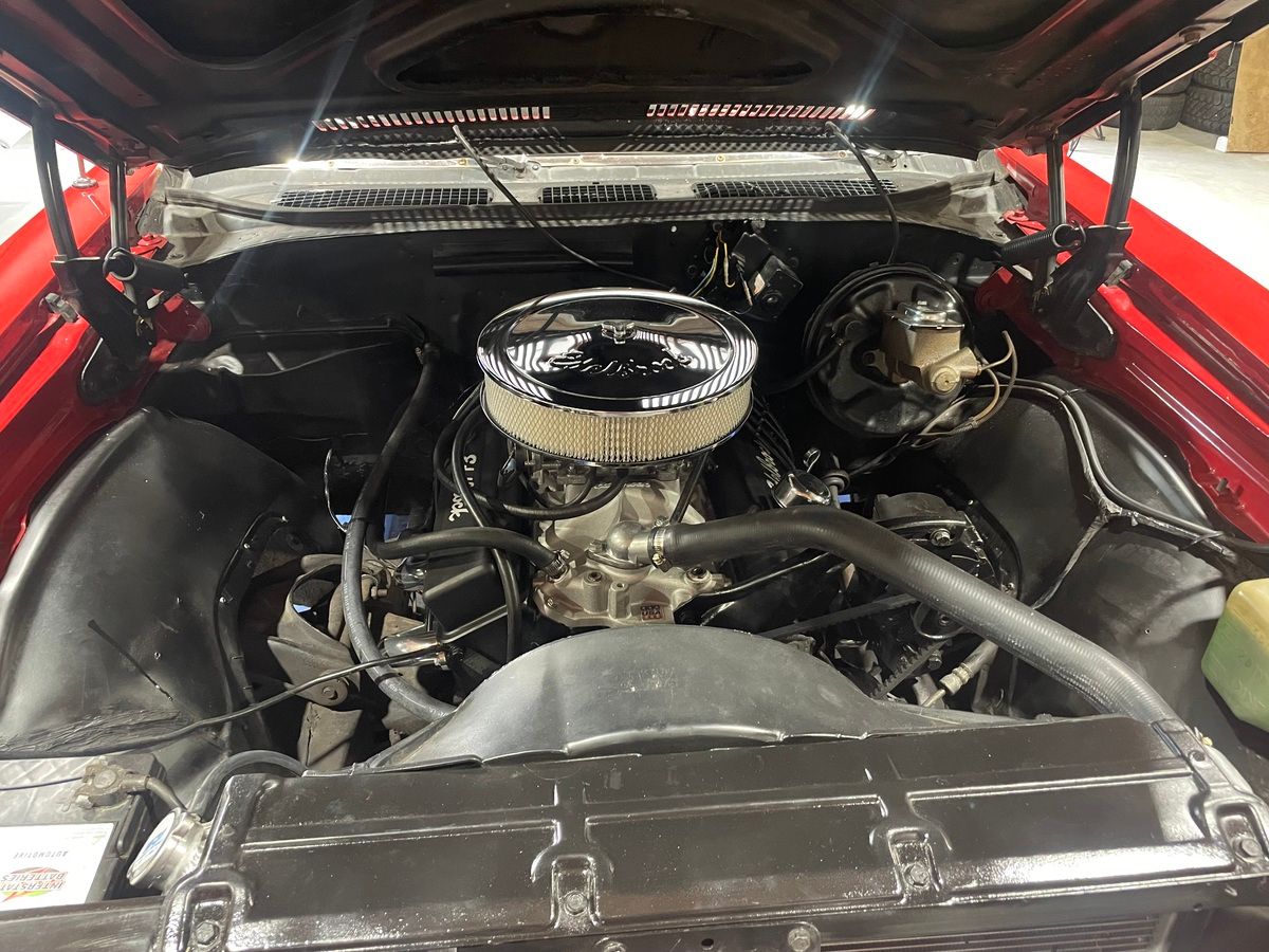 The engine of a red car with the hood up