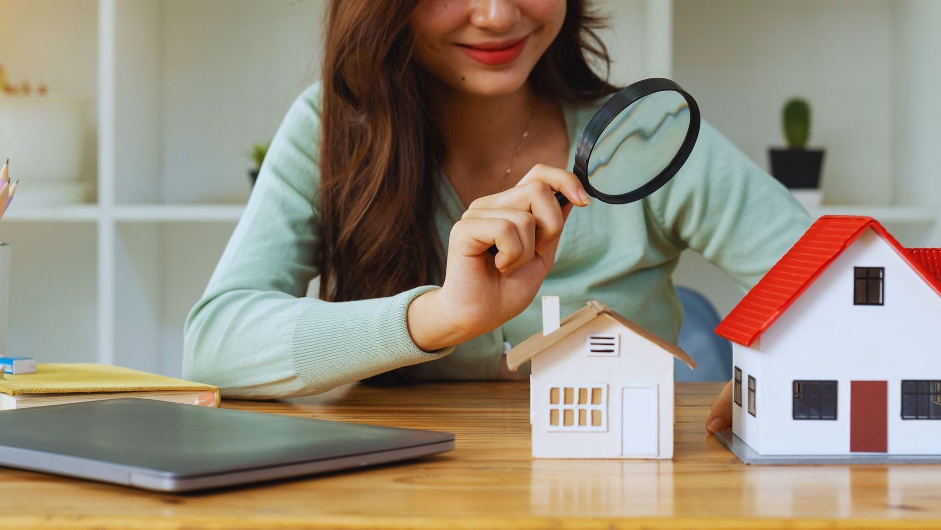 A woman looking at a rental house with a magnifying glass.