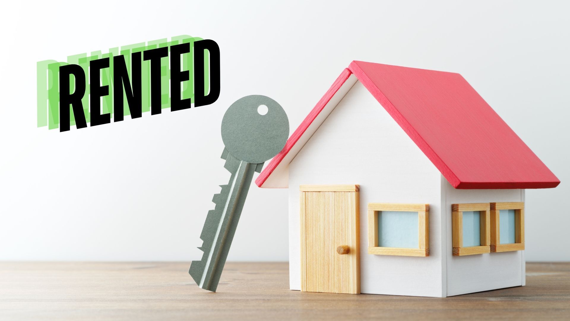 Miniature house with red roof, silver key, and bold 'RENTED' text on table, symbolizing rented property