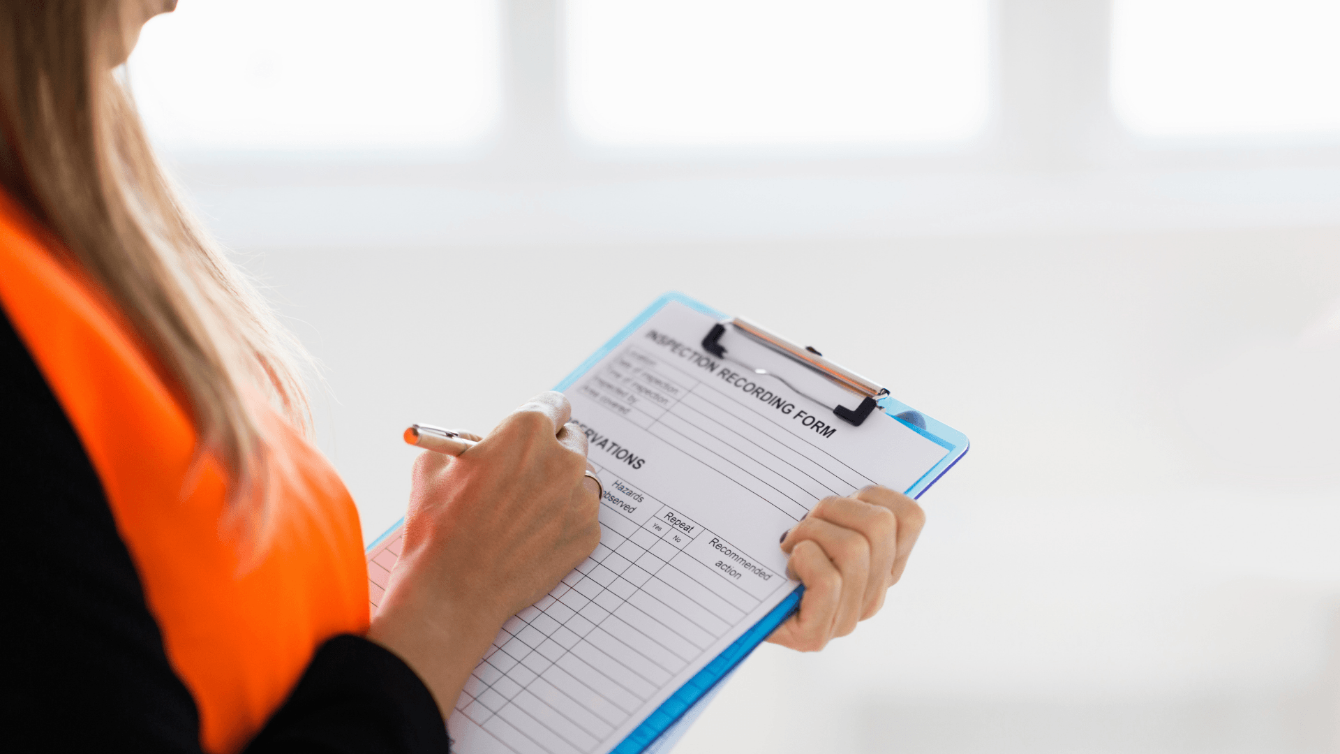 Tenant in high visibility vest diligently fills out an inspection form, with a softly blurred, brightly lit background.