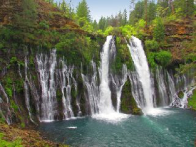 Burney Falls - Multi-stream waterfall flowing into serene turquoise pool surrounded by lush green foliage, rocky cliffs.