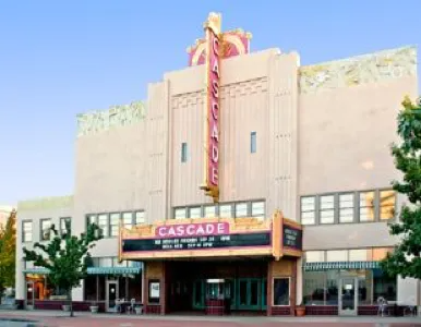 A photo of the cascade theatre's front facade, featuring art deco architectural style with a vertical neon sign that reads 