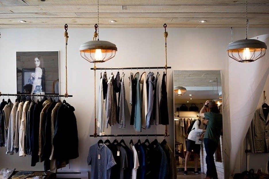 Elegant boutique with vintage lighting, diverse clothing, and browsing customers