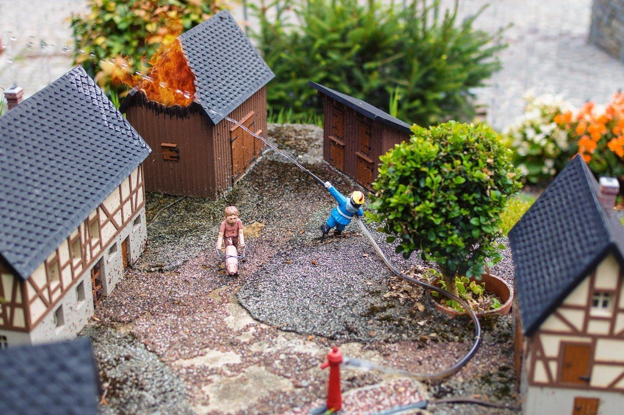 People in miniature rental home town scene, collaboratively extinguishing house fire.