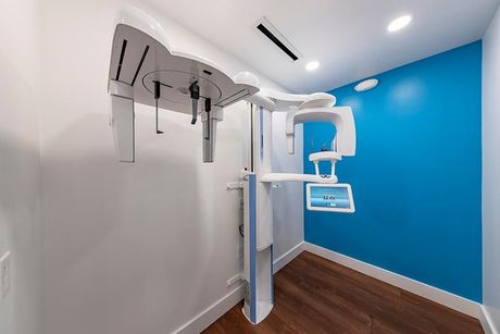 A room with a blue wall and a dental machine on the wall.