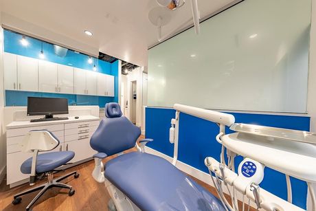 A dental office with a blue dental chair and a computer.