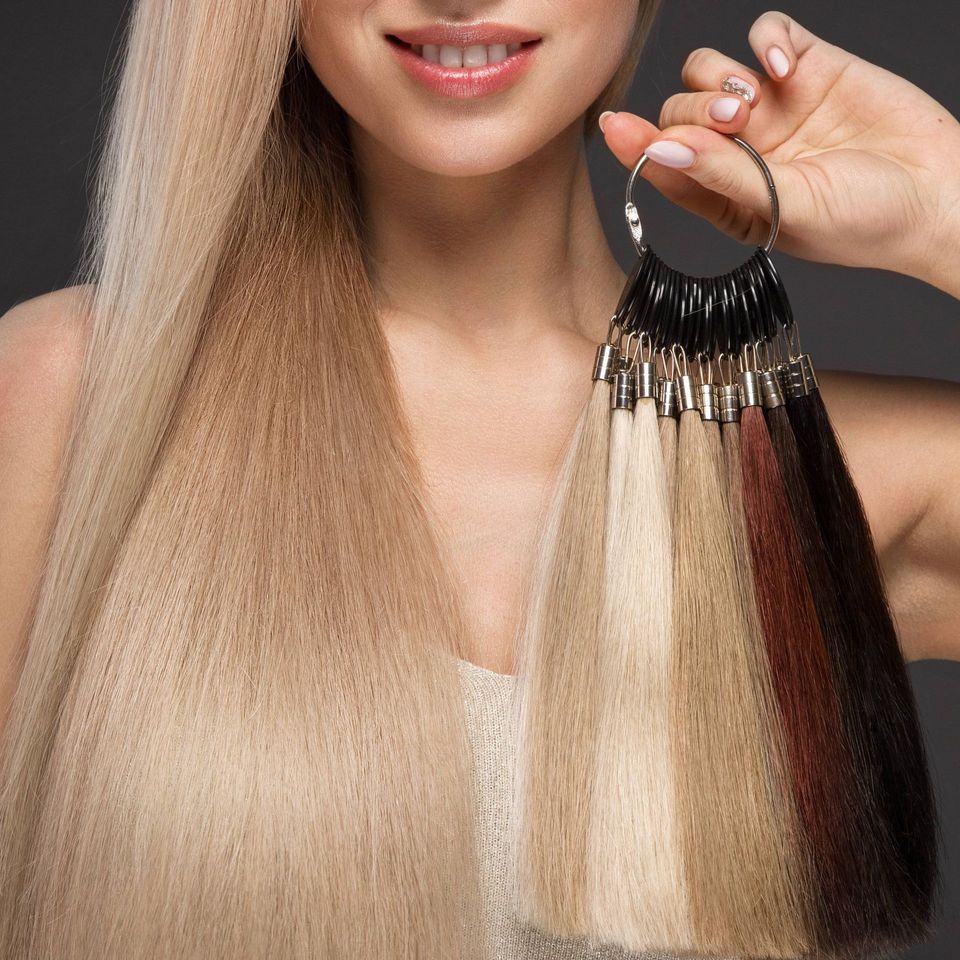 A woman with long blonde hair is holding a ring of hair extensions