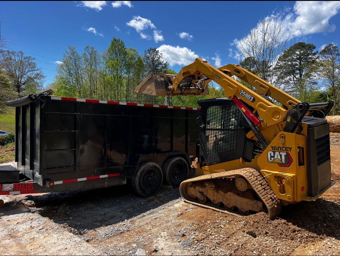 A bulldozer is loading a dumpster on a trailer.