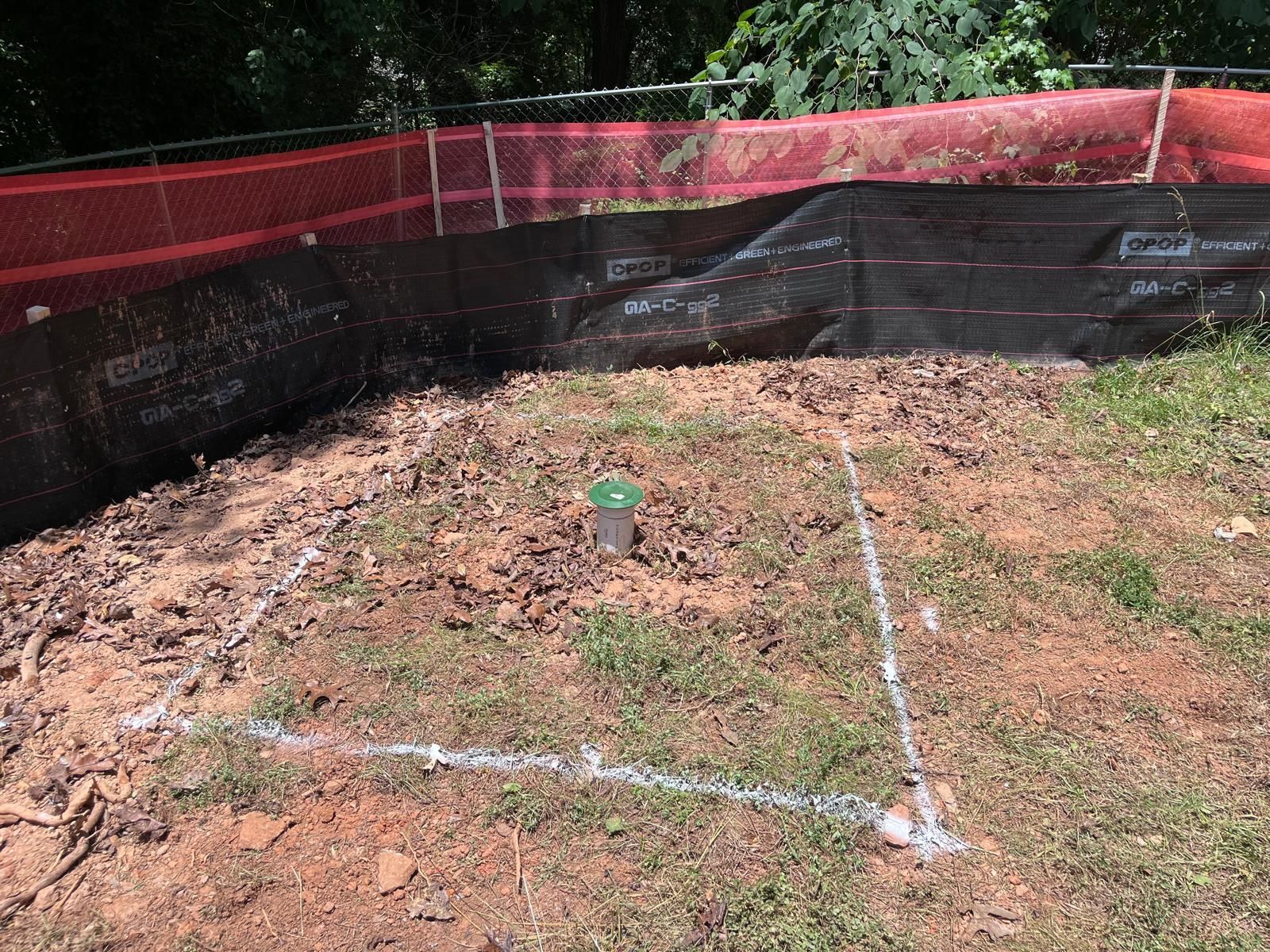 A square in the middle of a dirt field with a fence in the background.