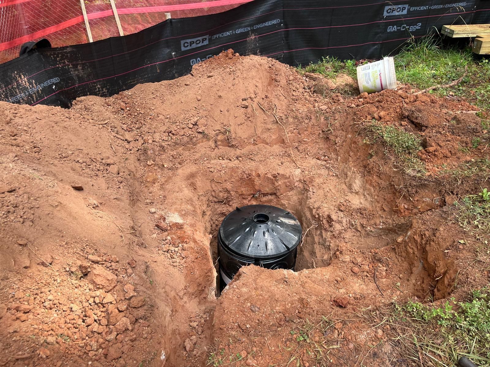 A drain pipe is being installed in a hole in the ground.