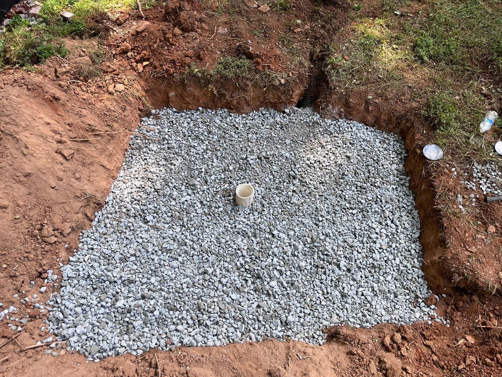 A hole in the ground filled with gravel and a pipe.