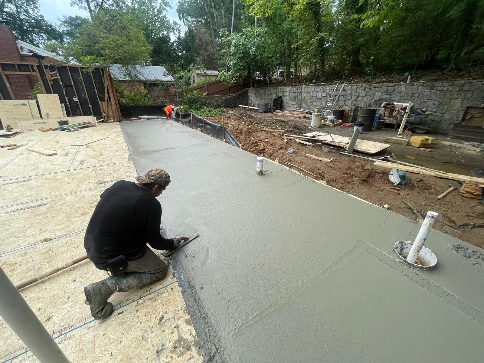 A man is kneeling down on a concrete surface.