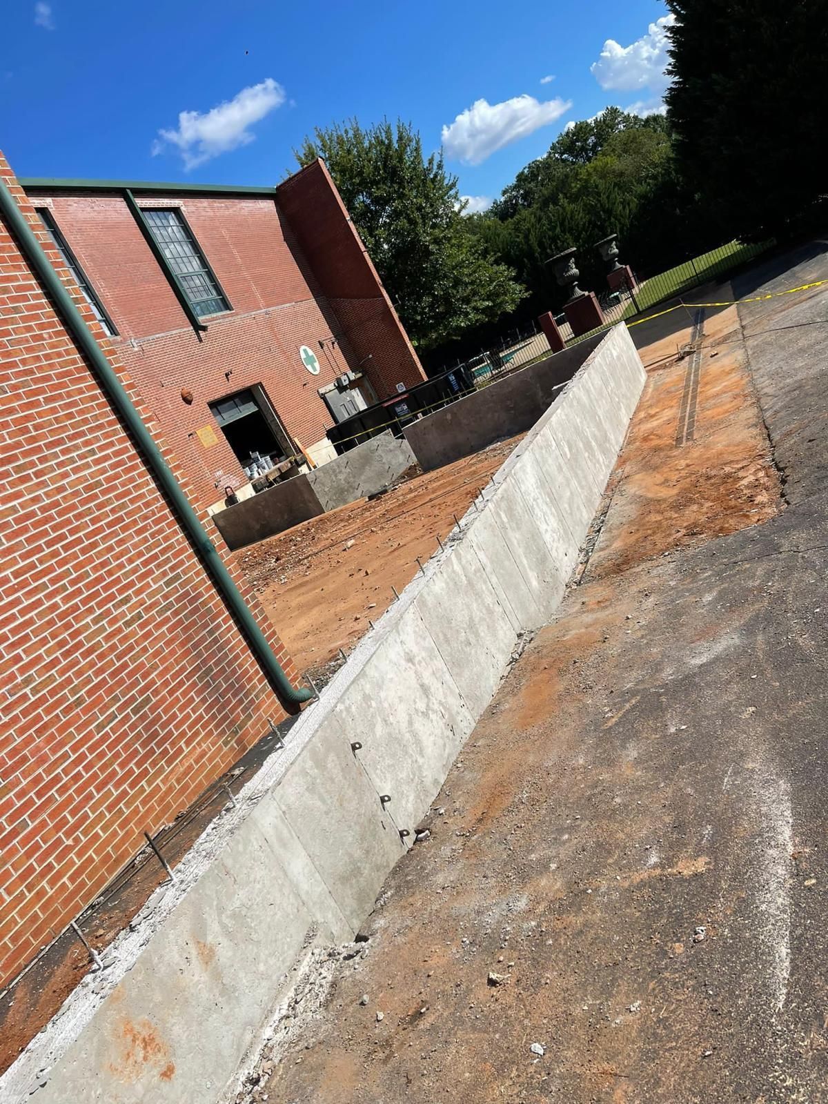 A concrete wall is being built in front of a brick building.