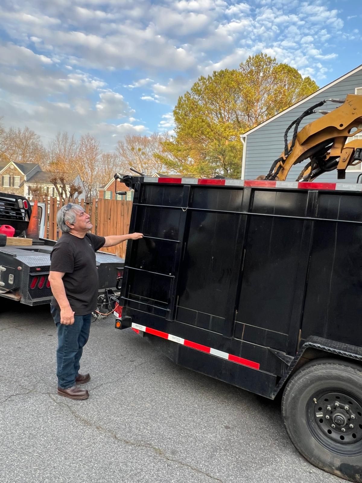 A man is standing next to a dumpster trailer.