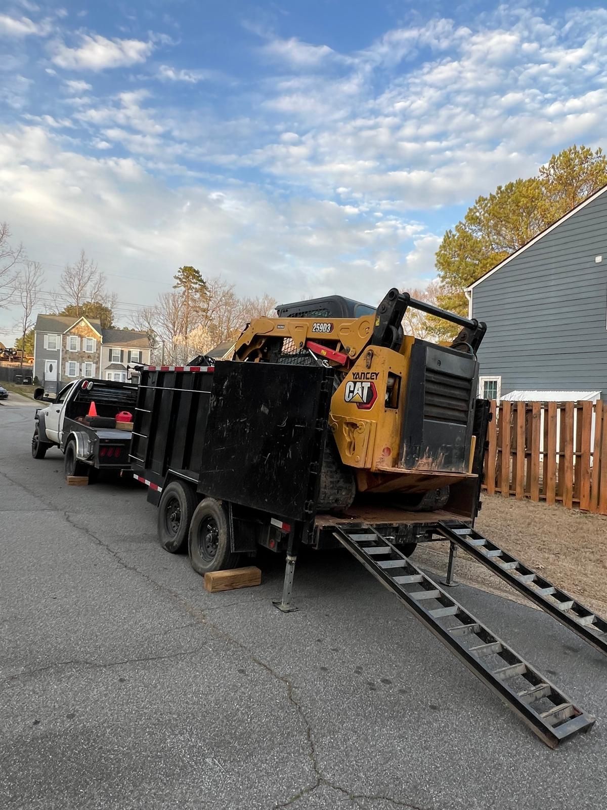 A dump truck is being towed by a cat machine on a trailer.