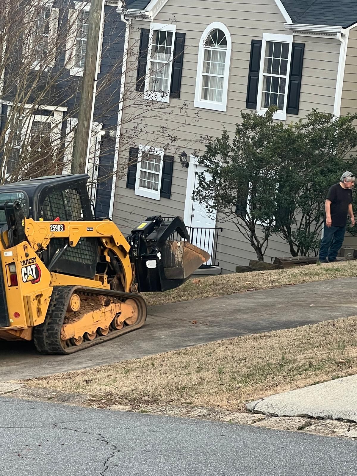 A bulldozer is parked on the side of the road in front of a house.