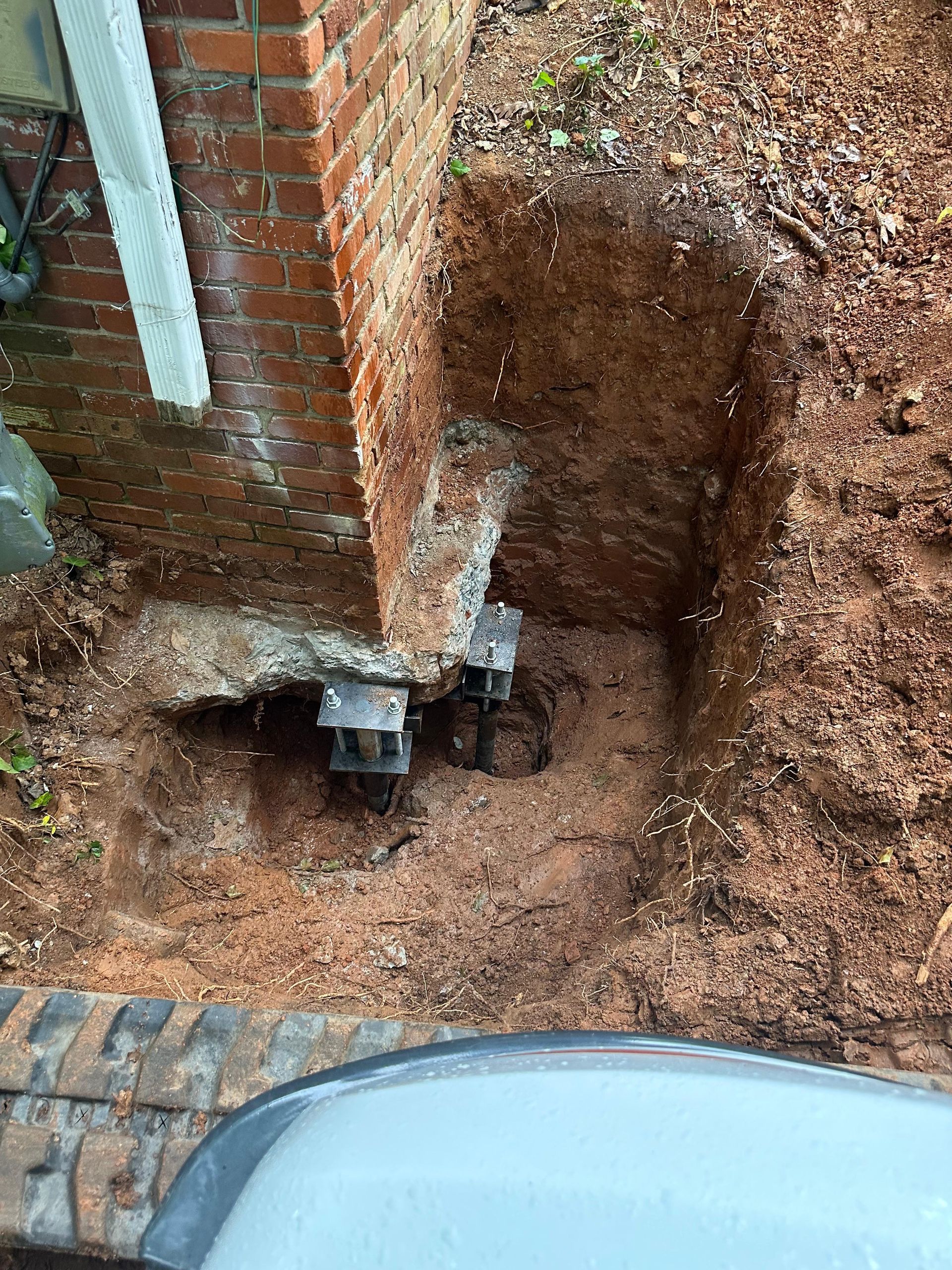 A hole in the ground next to a brick wall.