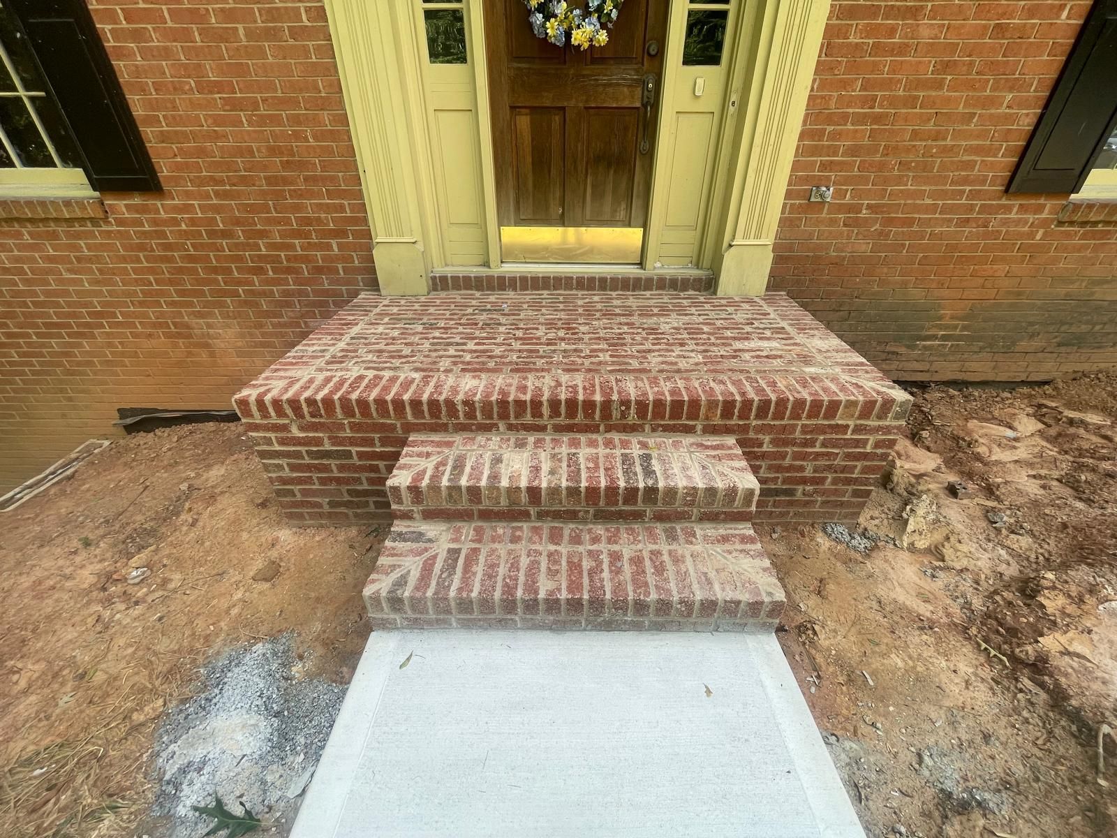 A brick walkway leading to the front door of a brick house.