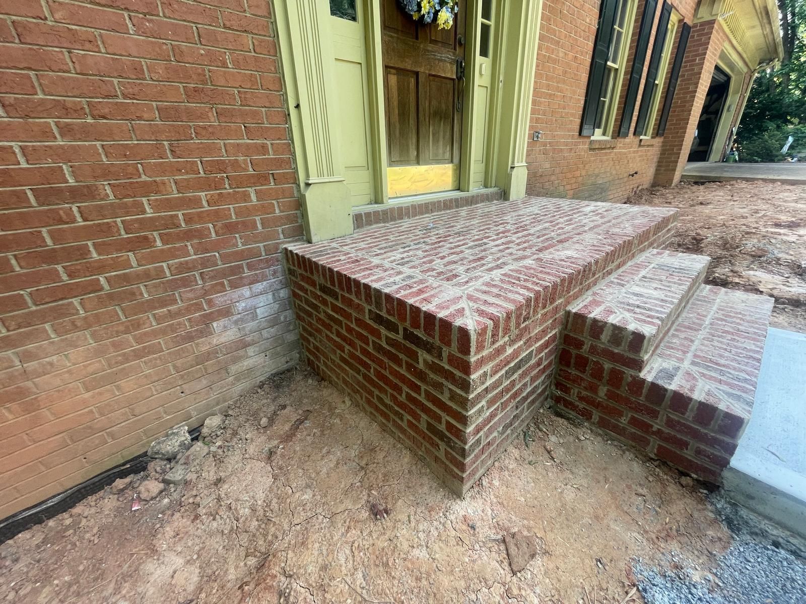 A brick porch with steps leading to the front door of a house.