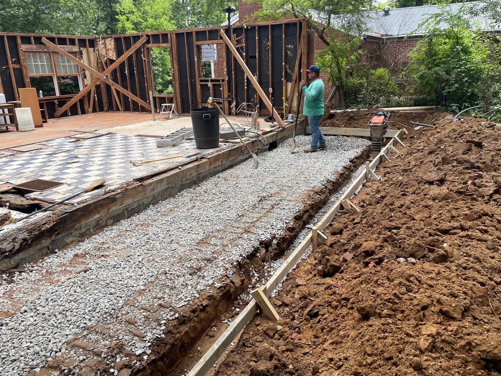 A man is standing in a pile of dirt in front of a house under construction.