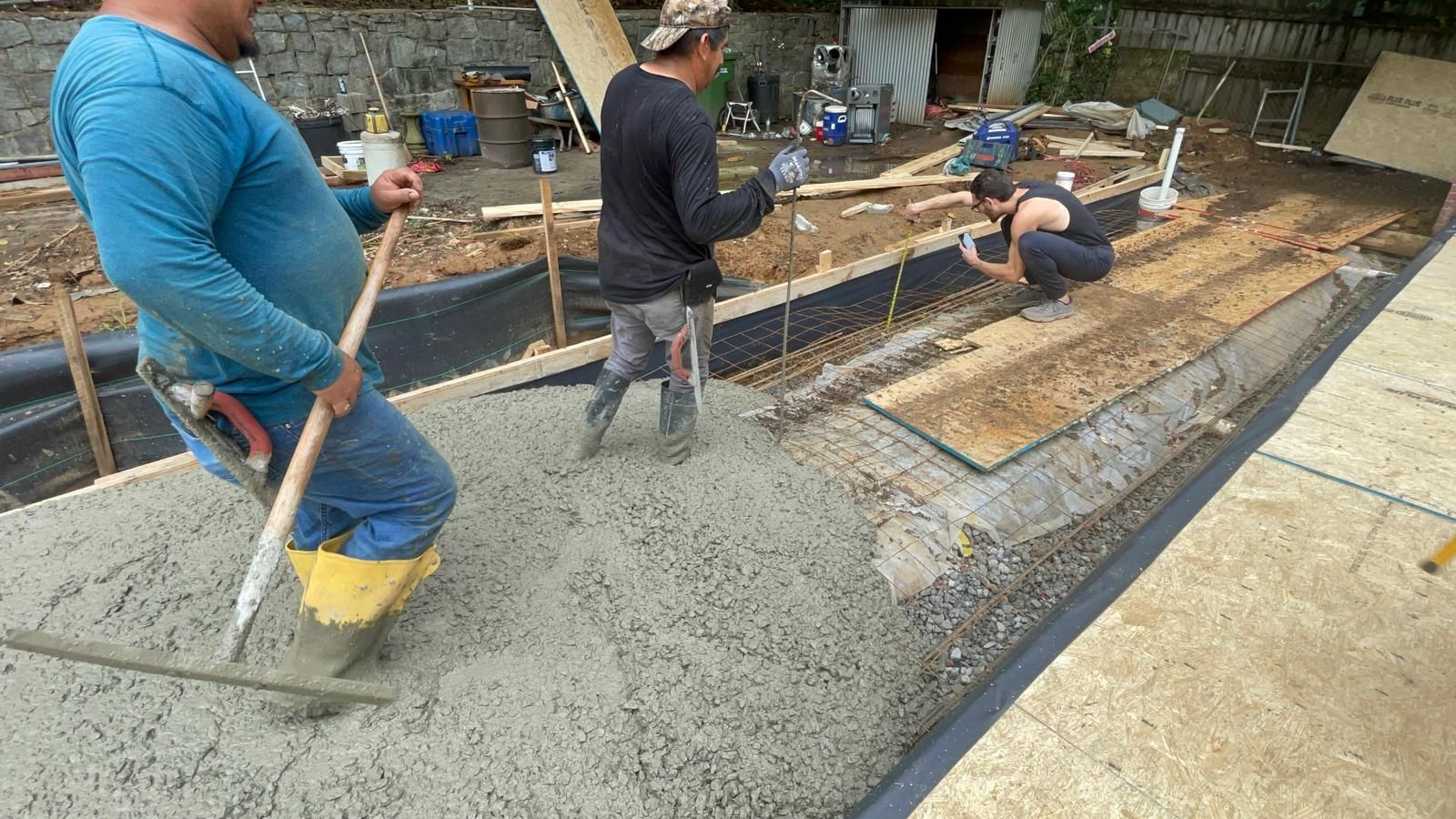 A group of construction workers are working on a concrete floor.