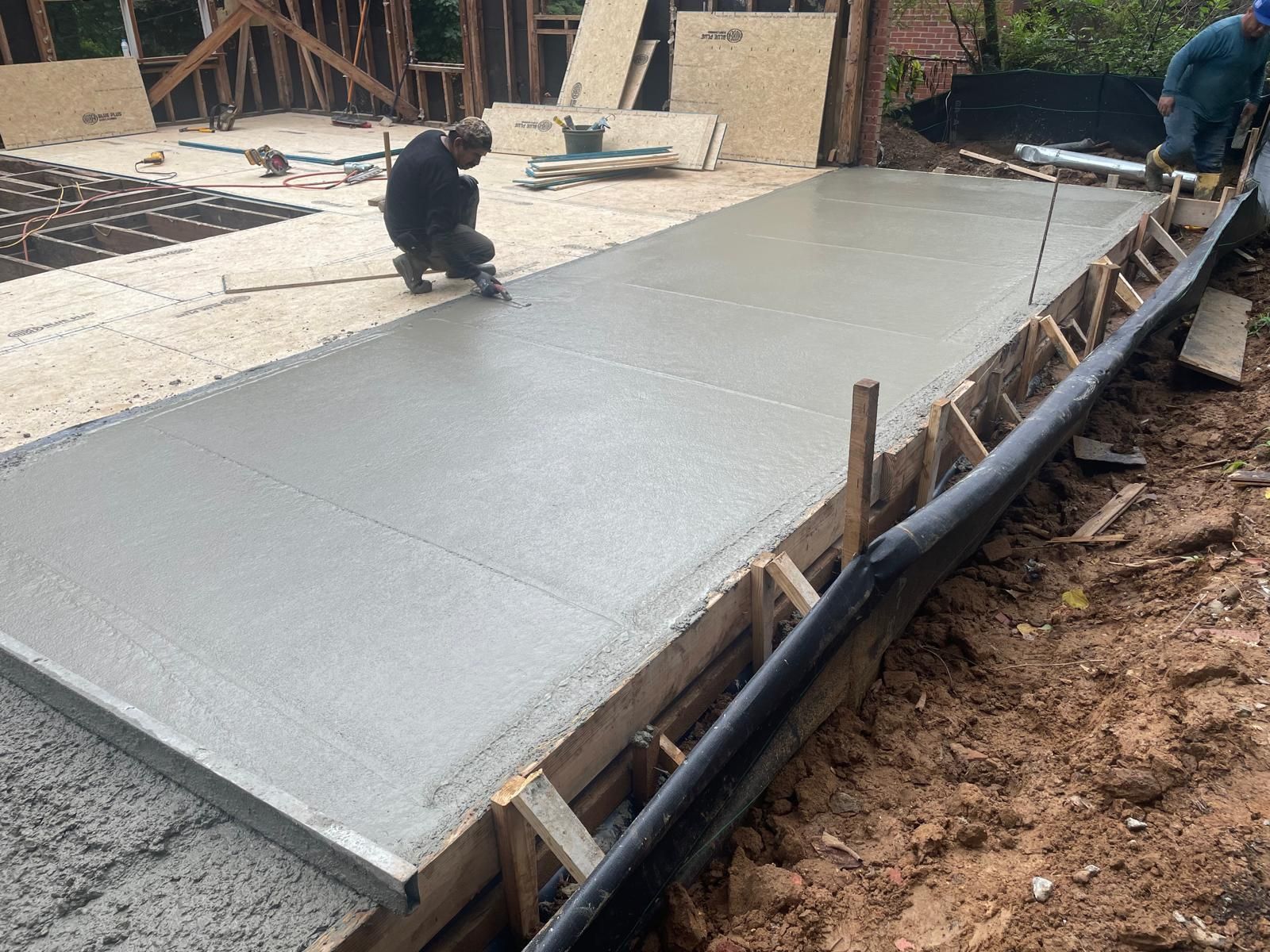 A man is laying concrete on a construction site.