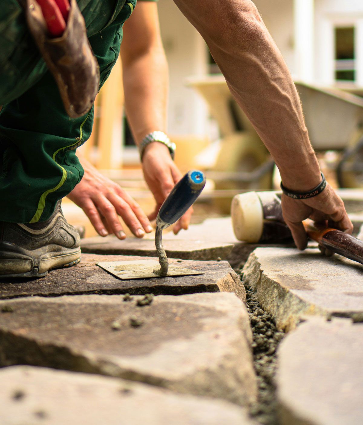 A man is using a trowel to spread cement on a stone floor.