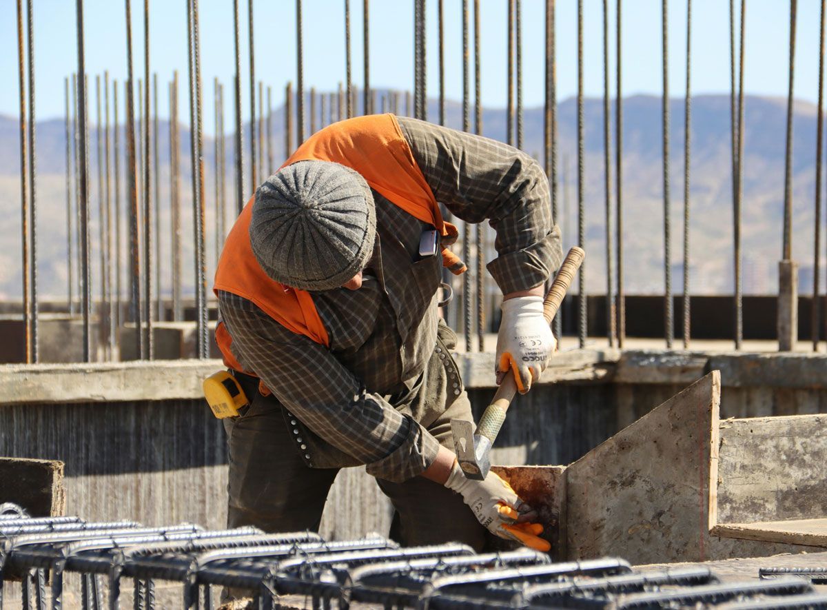 A man in an orange vest is working on a construction site.