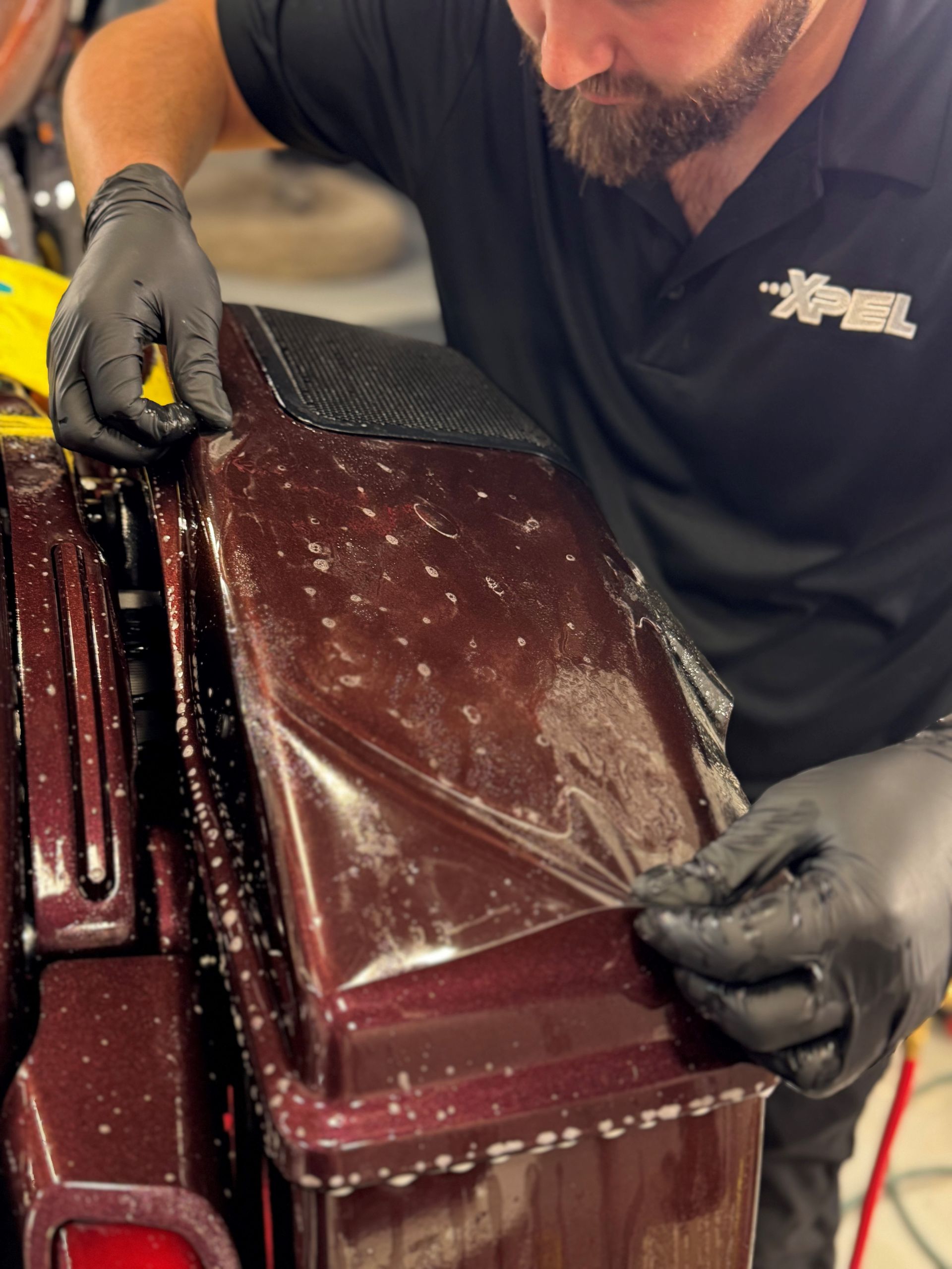 A man is spray painting a red car in a garage.