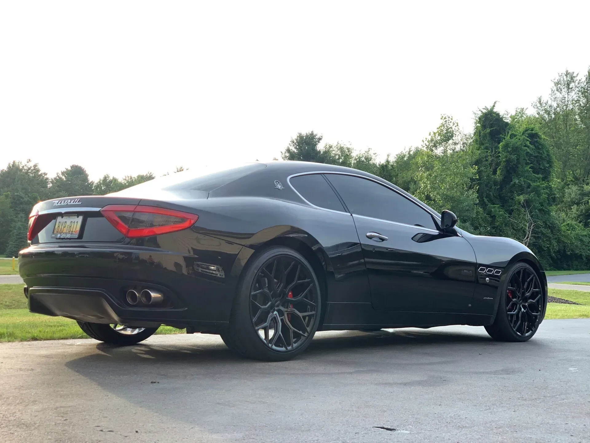 A black maserati granturismo is parked in a driveway.