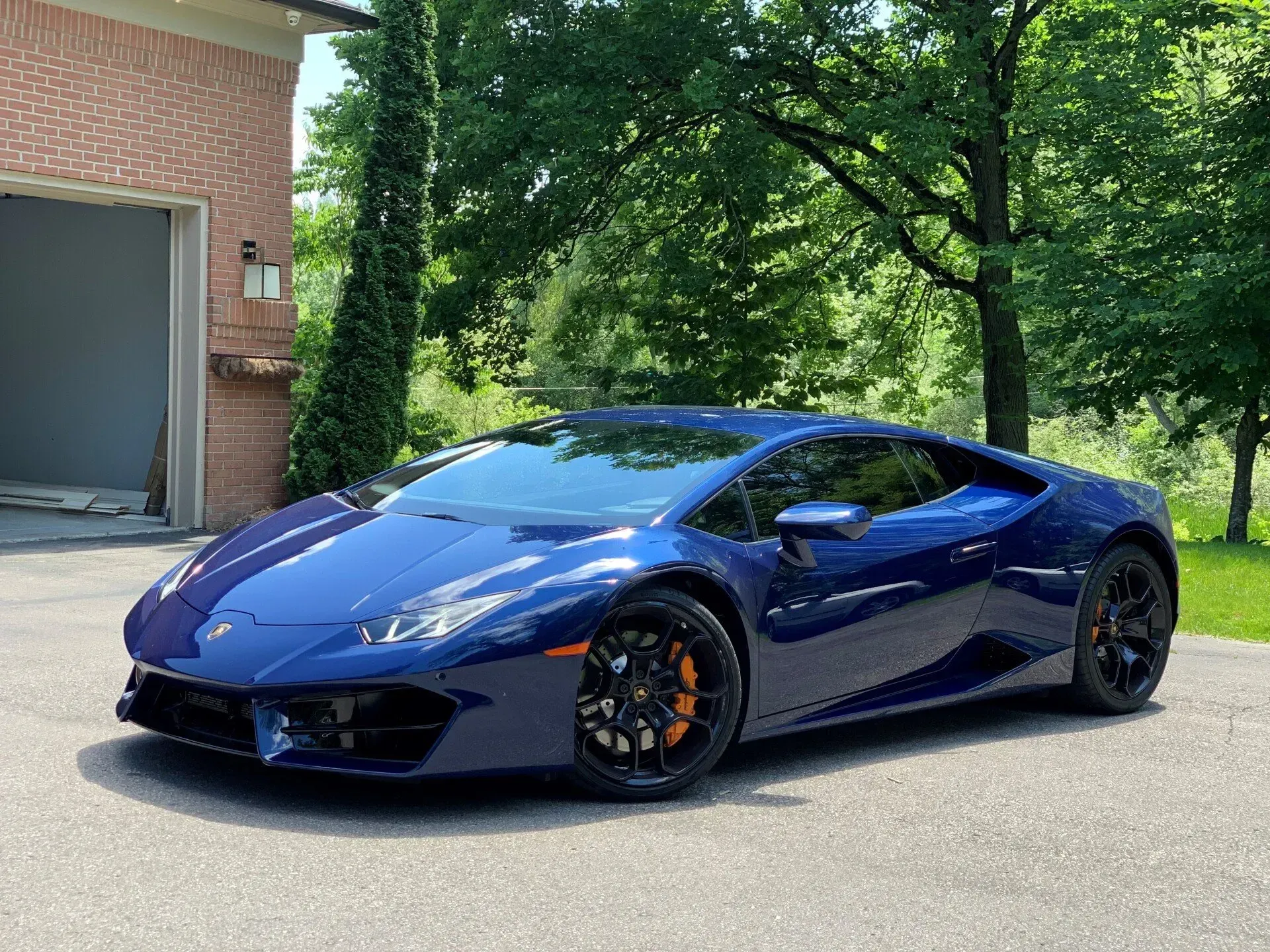 A blue lamborghini huracan is parked in front of a garage.