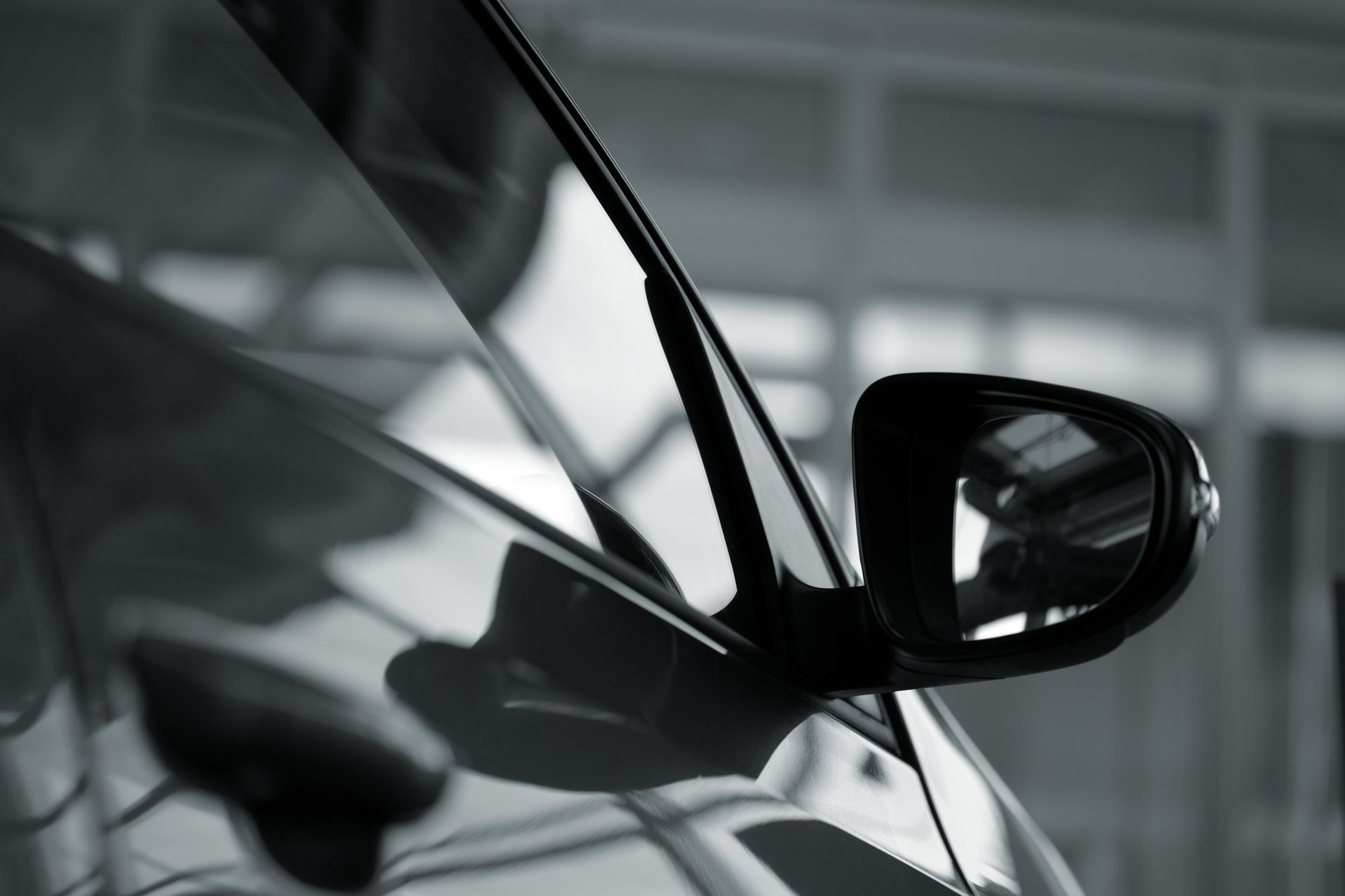 A black and white photo of a car 's side mirror